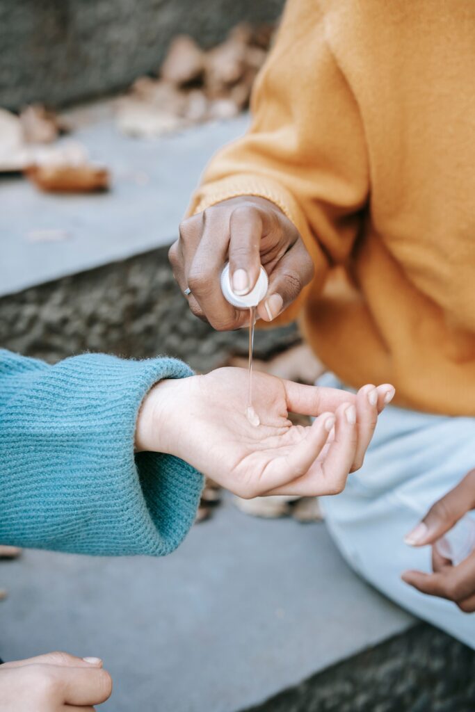 Close up of two women's hands sharing hand sanitizer outdoors, promoting hygiene