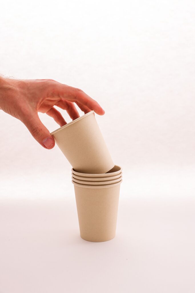 Close-up of hand stacking biodegradable paper cups, emphasizing sustainability